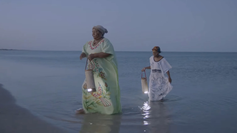 Women carrying lanterns filled with seawater.
