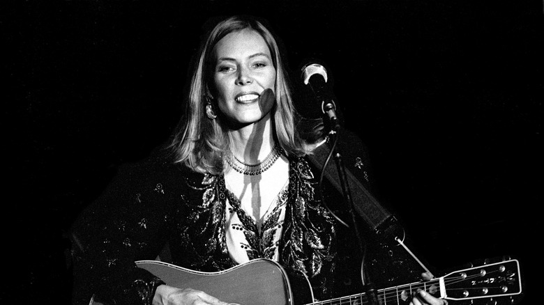 Joni Mitchell onstage with guitar and microphone