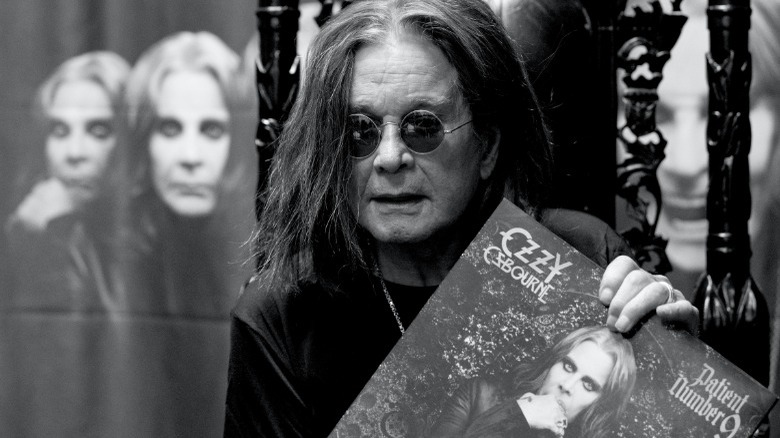 Ozzy Osbourne holding his album