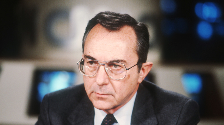 Moshe Arens, white Israeli man wearing large wireframe glasses with dark hair and receding hairline, wearing black suit and tie