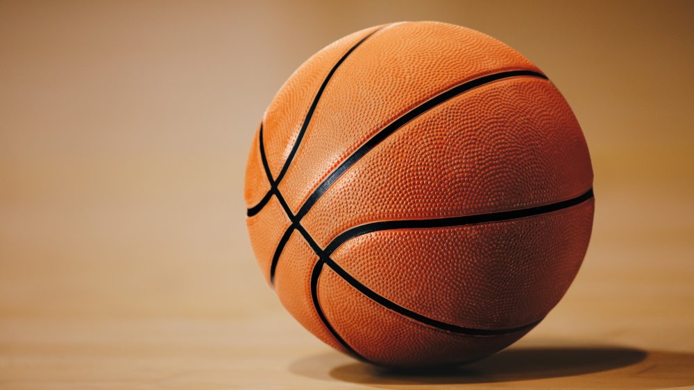 A basketball waits on an empty court