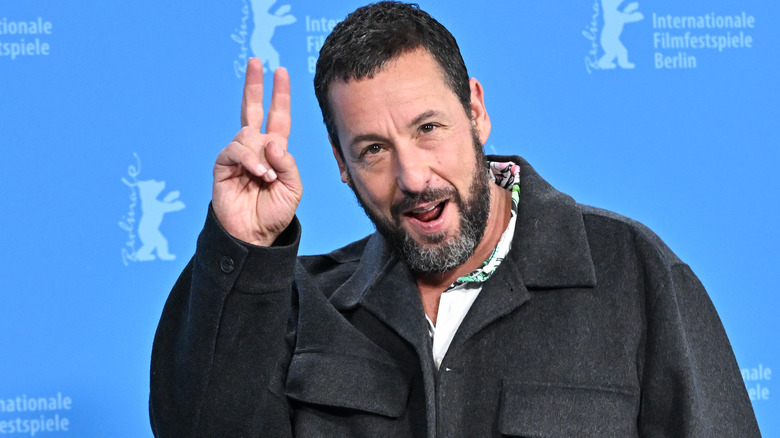 Adam Sandler smiling and doing peace sign