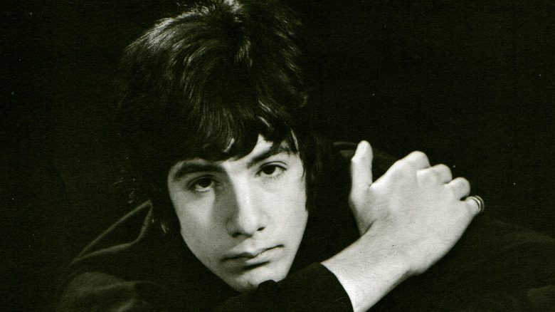 Young Cat Stevens leaning forward on arm black shirt and dark background