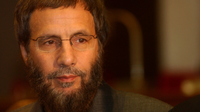 Close up of Cat Stevens with glasses, beard, and grey jacket