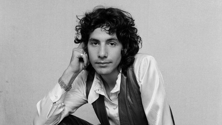Cat Stevens in white shirt and leather waistcoat sat with hand on head