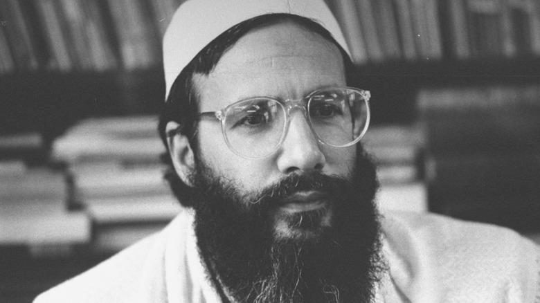 Cat Stevens with beard, glasses, and traditional Muslim dress with hat