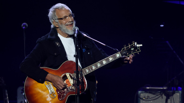 Cat Stevens smiling with acoustic guitar performing on stage