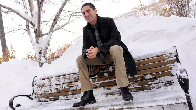 Nev Schulman sitting on a snow-covered park bench