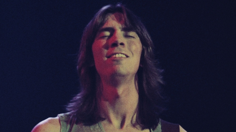 tom scholz plays guitar on stage with eyes closed