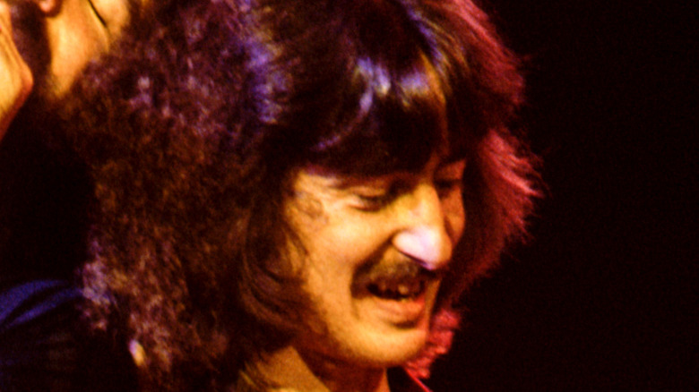 barry goudreau smiles and looks down on guitar on stage