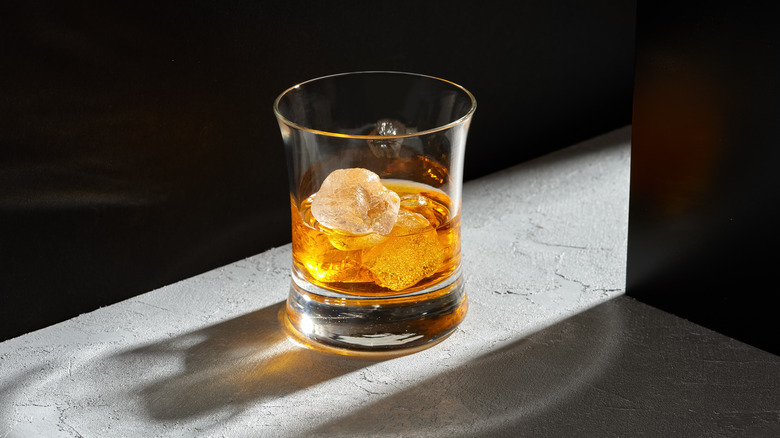A glass of whiskey backlit against black background