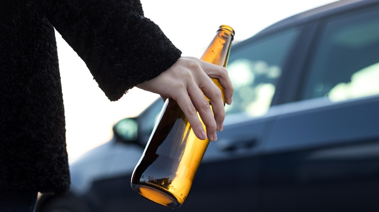 Hand of man walking holding a bottle