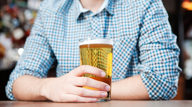 A man seated with a pint of beer in foreground