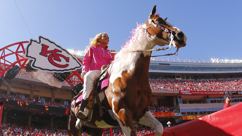 cheerleader riding Kansas City Chiefs mascot Warpaint