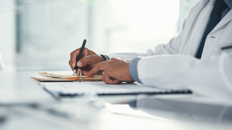 doctor writing on clipboard