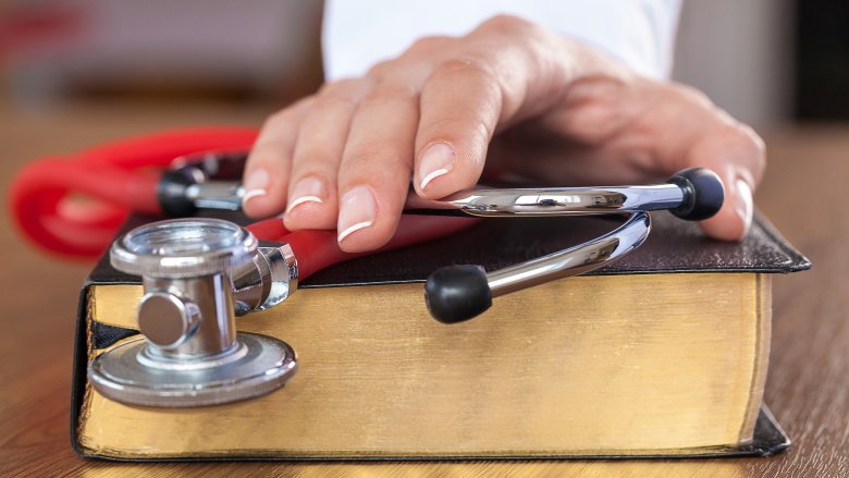 hand with medical instruments on Bible