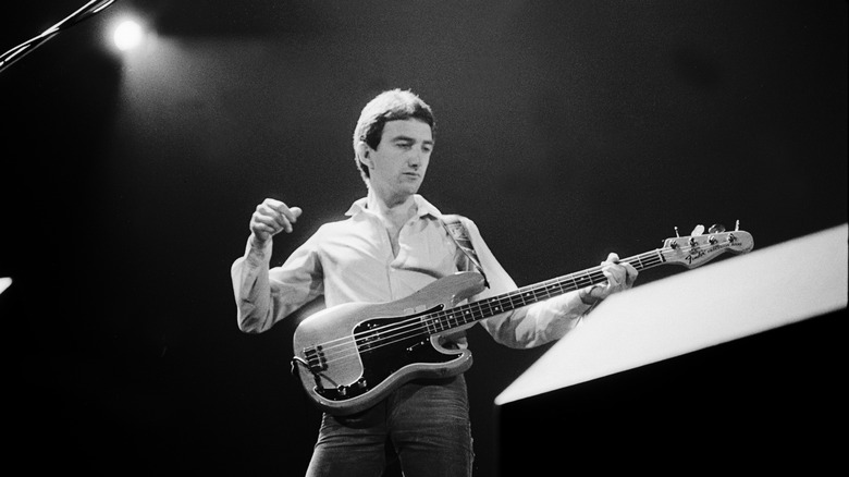 John Deacon on stage with bass guitar