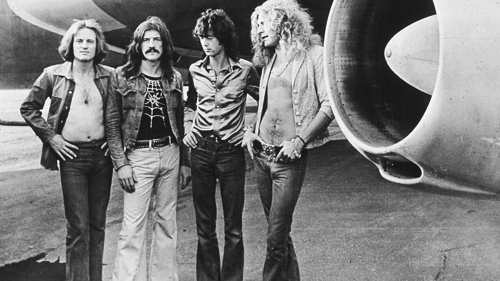 Led Zeppelin posing next to a plane