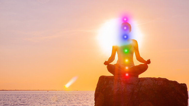 Woman meditating with chakras in sunset