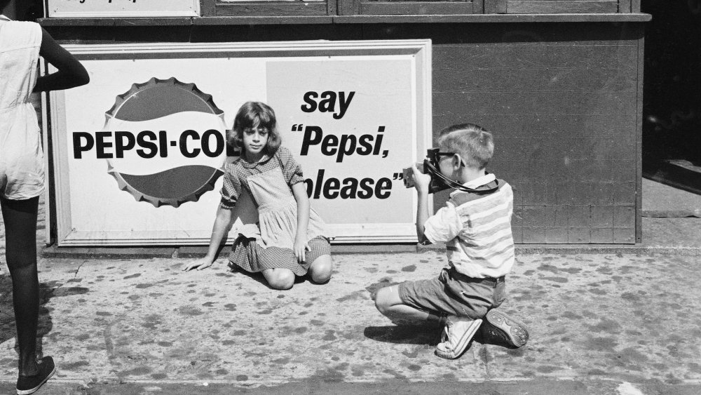 Two children in front of a Pepsi advertisement