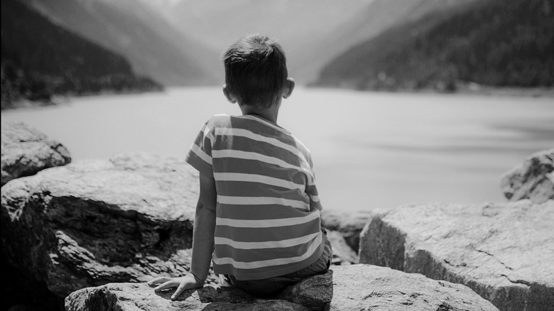 Little boy staring at lake