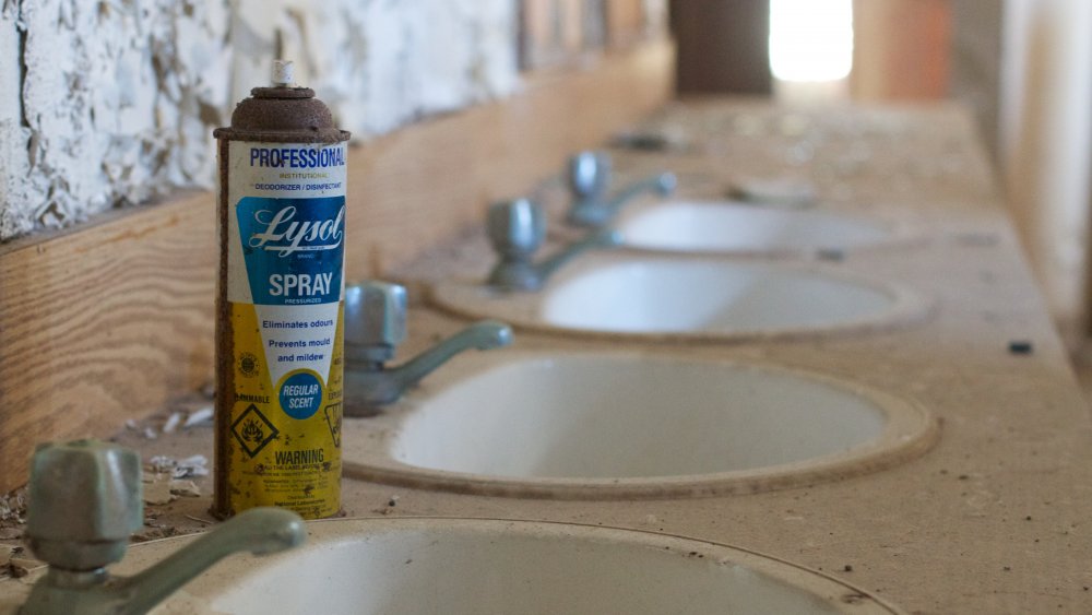 A rusted can of lysol in a dingy bathroom