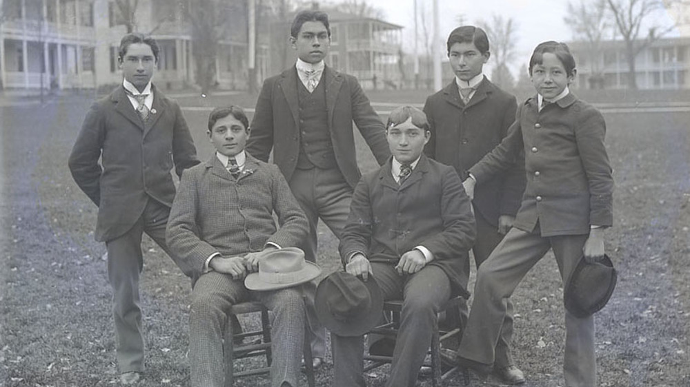 Carlisle Students standing and sitting, dressed in suits