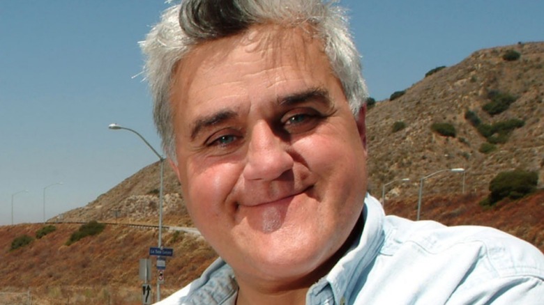 Jay Leno smiling outside wearing denim shirt