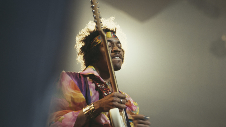 Jimi Hendrix bathed in a spot light while playing guitar