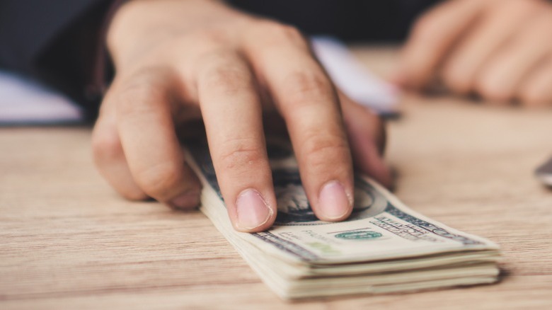 Hand pushing money across table
