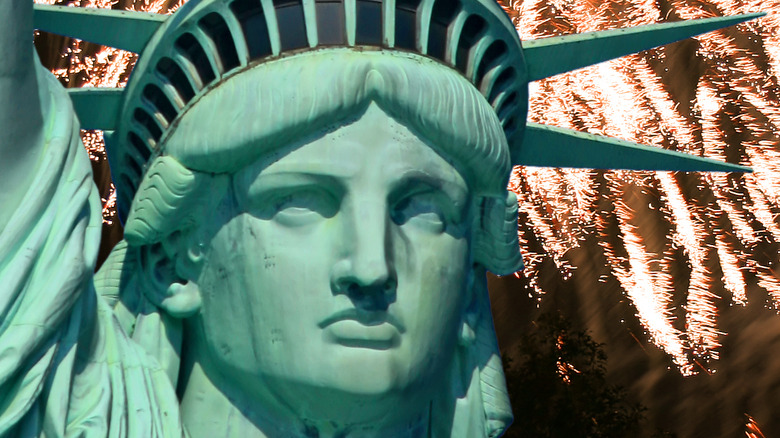 The statue of liberty with fireworks in the background