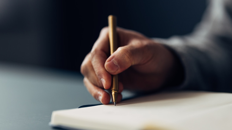 A hand writing with a pen