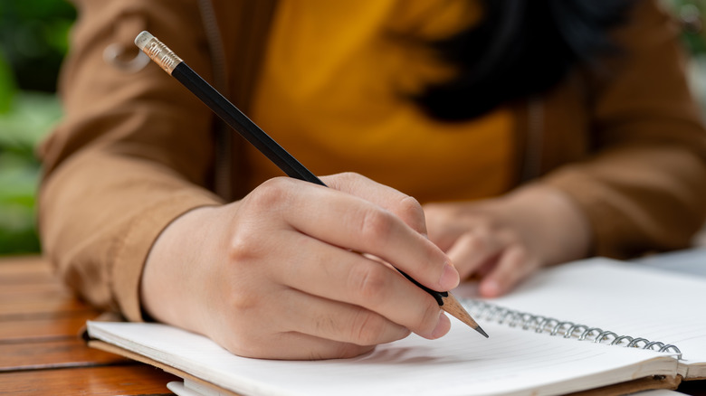 A woman writing with a pencil