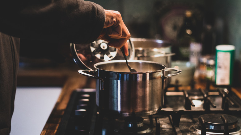 A person cooking stew in the kitchen at night