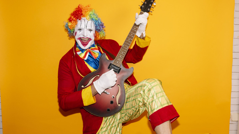 A clown playing the guitar indoors