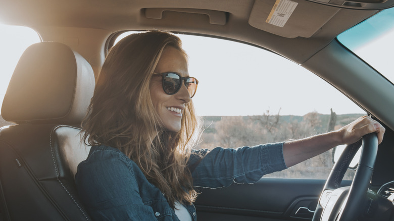 A smiling woman with shades in the driver seat