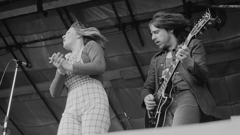 Les Harvey playing guitar on stage with a woman singer