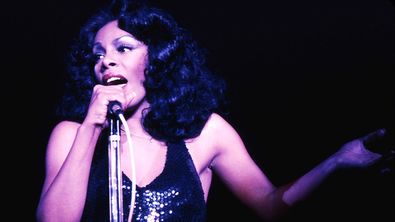 Donna Summer singing into microphone in a sequined dress