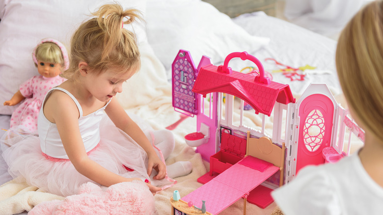 girls playing with pink dollhouse
