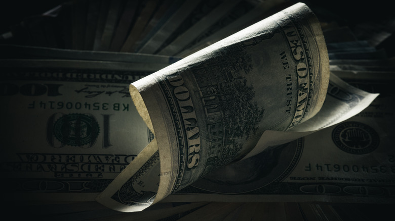 Closeup of curled U.S. bill in dark lighting