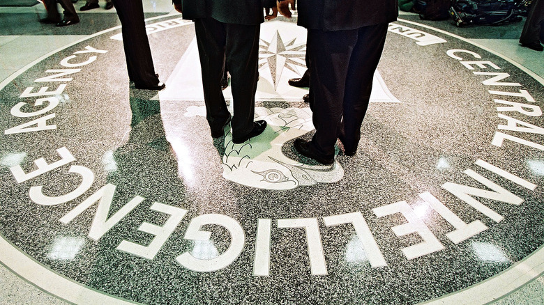 President George W. Bush, Central Intelligence Agency Director George Tenet and others stand on the seal of the Agency March 20, 2001