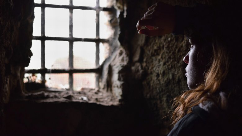 woman looking out medieval prison cell