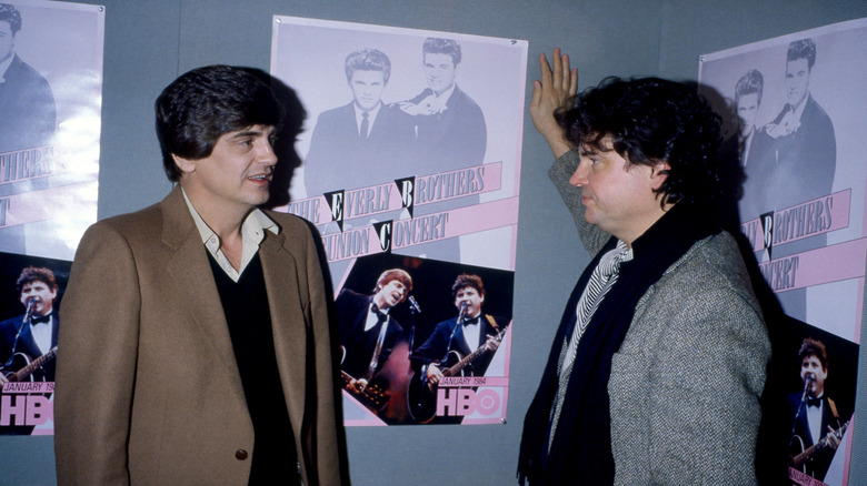 Don and Phil Everly of The Everly Brothers talking awkwardly in front of poster for their reunion concert