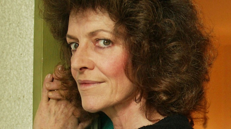 Closeup of Cathy Smith leaning against a wall and smirking