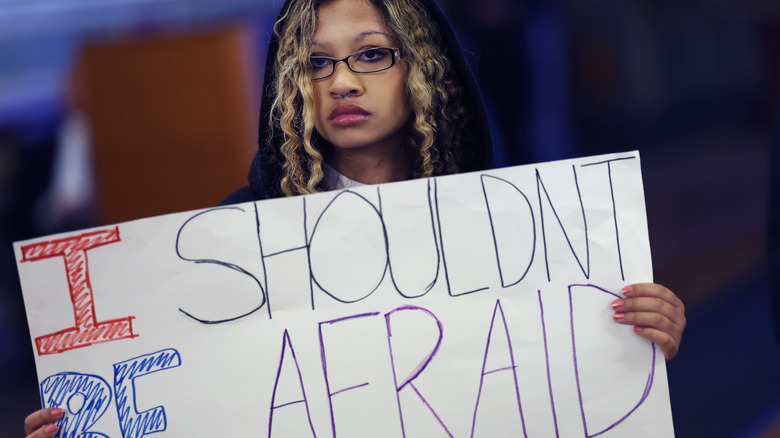 student holding a sign saying I shouldn't be afraid