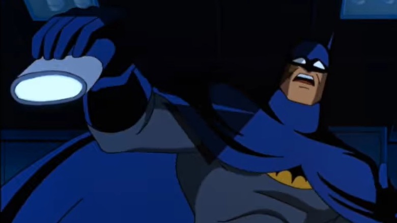 Batman holding a flashlight with a horrified look on his face
