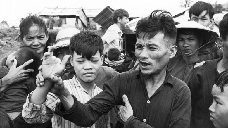 A man holding up his son's maimed hand, a victim of the the My Lai Massacre
