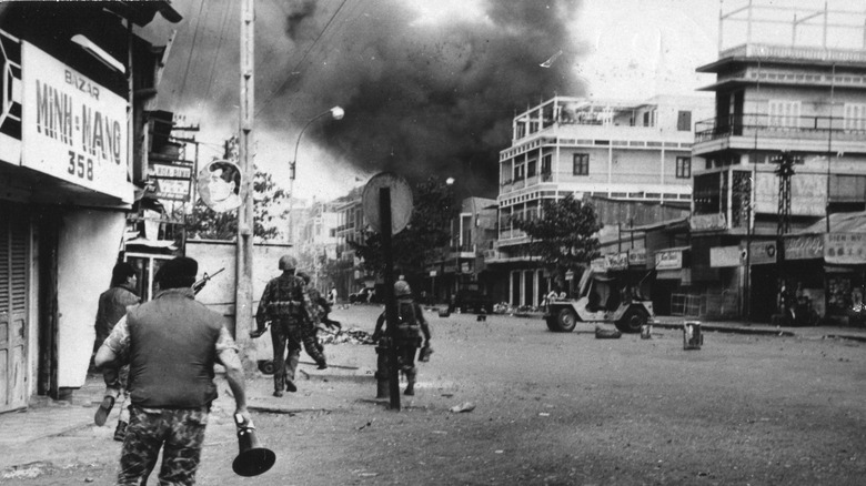 Soldiers running through a city street towards billowing smoke during the Tet Offensive