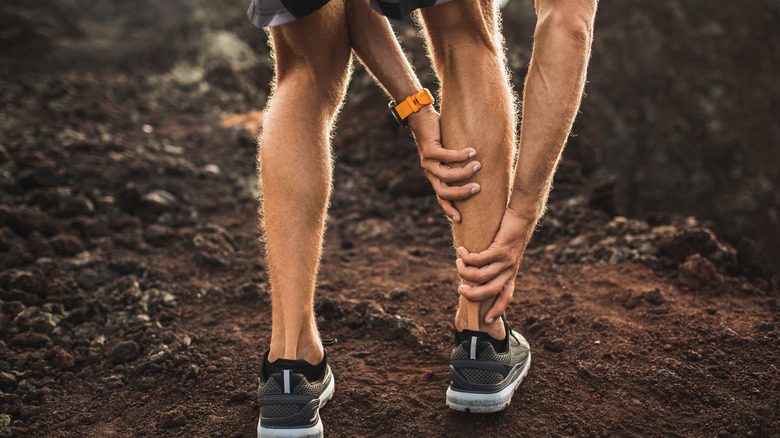 man bending holding calf Achilles