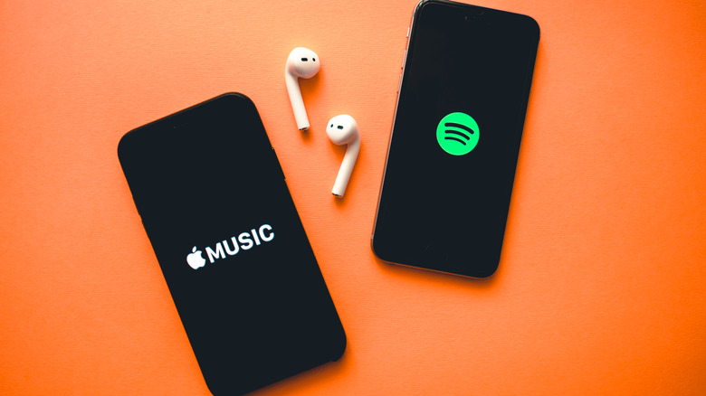 Two iPhones with earphones and Apple Spotify logos